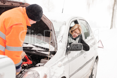 Man repairing woman's car snow assistance winter