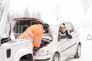 Man repairing woman's car snow assistance winter