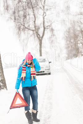 Woman with warning triangle car snow breakdown