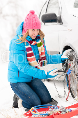 Woman putting chains on car winter tires