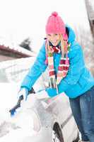 Woman cleaning car hood of snow brush