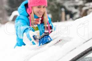Woman wiping snow car window using brush
