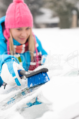 Woman wiping car windshield using brush snow