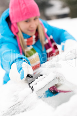 Woman brushing snow from car windscreen winter