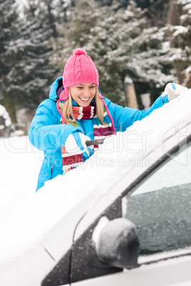 Woman cleaning car windshield of snow winter