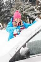 Woman cleaning car windshield of snow winter