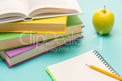 Pencil on notepad with school books apple