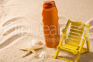 Suntan lotion container and seashells on sand