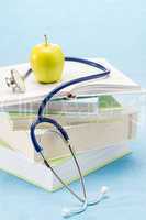 Medical books, apple and stethoscope