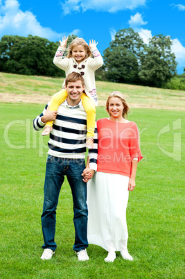 Family of three posing against natural background