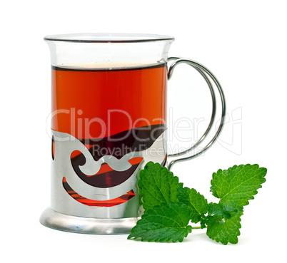 Tea in a glass holder and a sprig of lemon balm