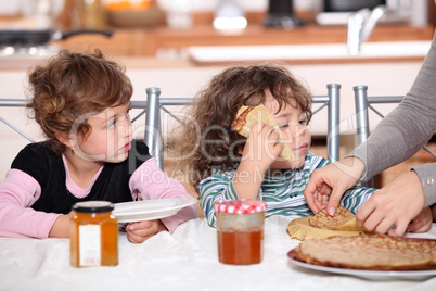 Two children at kitchen table having breakfast