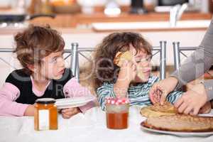 Two children at kitchen table having breakfast