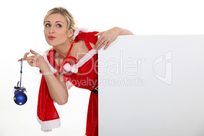 Woman dressed as Mrs. Claus and holding a blank board