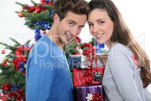 Excited young couple stood by the Christmas tree