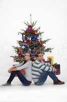 Couple sitting in front of their Christmas tree
