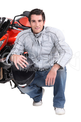Man kneeling by motor bike