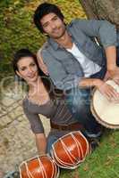 Couple playing the drums outside