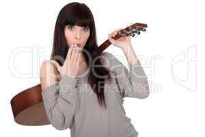young woman carrying guitar over shoulder with hand before mouth