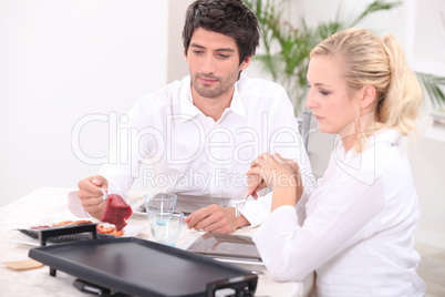 Couple cooking meat on hotplate