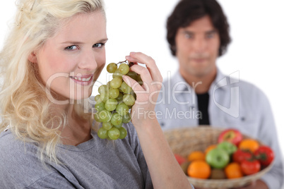 pretty smiling blonde eating grapes