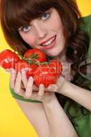 portrait of red-haired girl posing with bunches of tomatoes