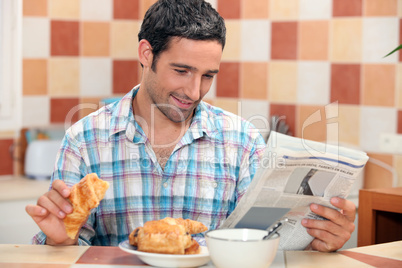Man reading the newspaper while having breakfast