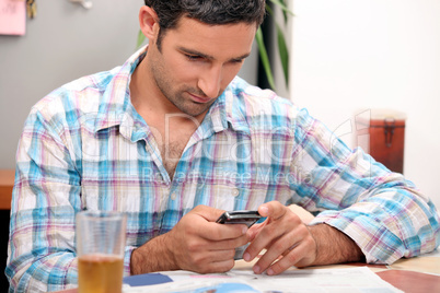 Man reading magazine and sending text message