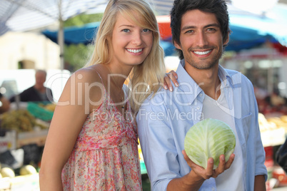Couple in a market with a cabbage.