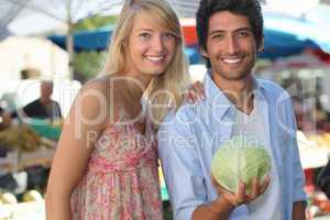 Couple in a market with a cabbage.