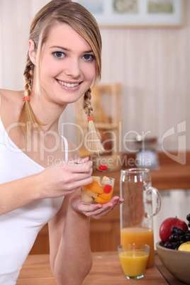 Woman eating a salad of fruits