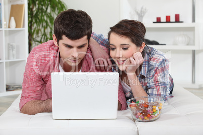 Young couple watching a film on their laptop