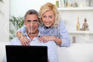 Mature couple using laptop at home