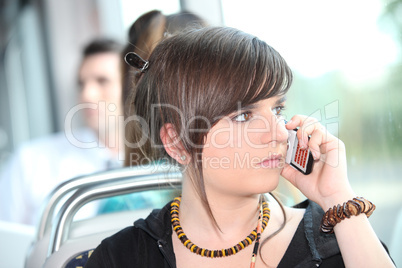 Trendy young woman using her cellphone on a tram