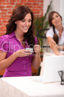 A woman having coffee while looking at her laptop