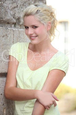 A nice blond posing by a wall.