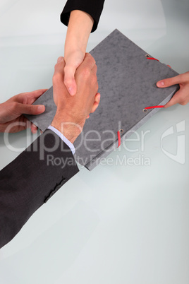 Business people shaking hands over a folder