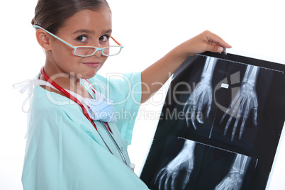 Young girl dressed in hospital scrubs examining an X ray