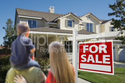 Family Looking at New Home with For Sale Sign