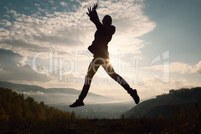 Happy young woman jumping at the sunset