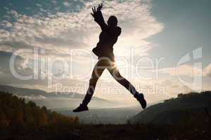 Happy young woman jumping at the sunset