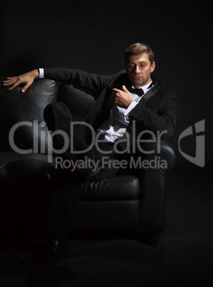 Handsome man in a tuxedo on couch