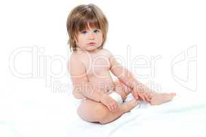 Adorable baby girl sitting up wearing a diaper