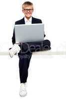 Smartly dressed young kid working on a laptop