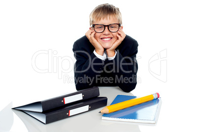 Bespectacled boy posing with files on his desk