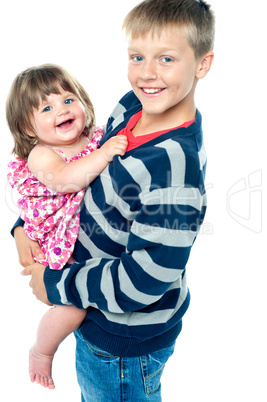 Loving young brother carrying his sweet little toddler sister