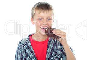 Fashionable young boy eating chocolate cookie