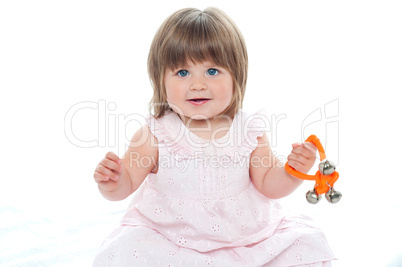 Healthy baby girl sitting on floor playing with rattle