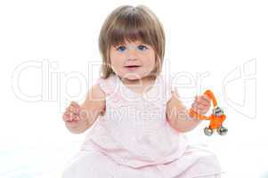 Healthy baby girl sitting on floor playing with rattle