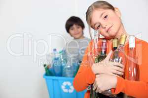 A girl and a boy recycling glass bottles